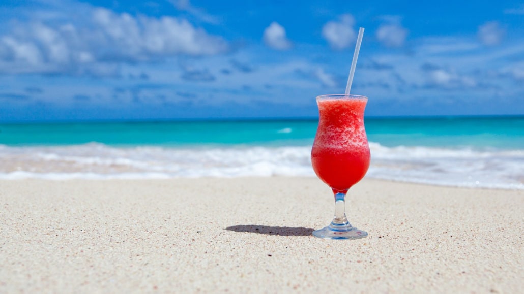 verre de cocktail posé sur une plage paradisiaque
